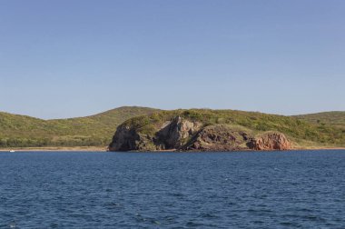 Japon denizinden güneşli bir günde Russkiy adasının engebeli kıyı şeridi