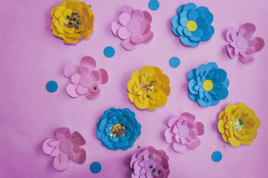 Yukarıdan pembe arkaplandaki renkli kağıt çiçeklerin görüntüsü