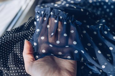 Bir kadının eli şifon fırfırlı elbisenin eteğini tutuyor.