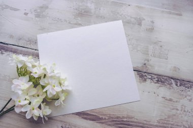 Çiçek açmış ortanca çiçeklerinin dalları ahşap zemin üzerinde boş beyaz kağıtlar süslüyor.