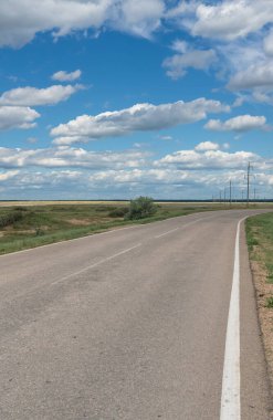 Kırsal bölgedeki boş asfalt yolu ve güneşli bir günde bulutlu manzara