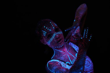 Sanat kadını ultraviyole ışıkta kozmos. Bütün vücudu renkli damlacıklarla kaplı. Karanlıkta poz veren kız. Gürültü, odak dışı