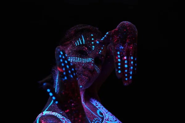 Art woman cosmos in ultraviolet light. Entire body is covered with colored droplets. Girl posing in the dark. Noise, out of focus