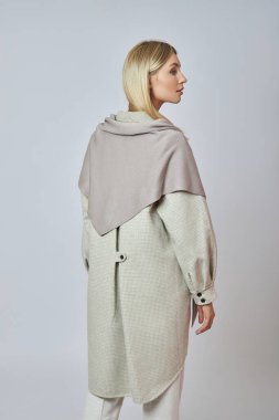 Boynunda ve omuzlarında kış atkısı olan güzel bir kadın. Soğuk sonbahar havası için kıyafet.