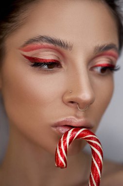 Parlak kırmızı göz makyajlı kadın ellerinde karamel, hatta güzel kaşları ve uzun kirpikleriyle.