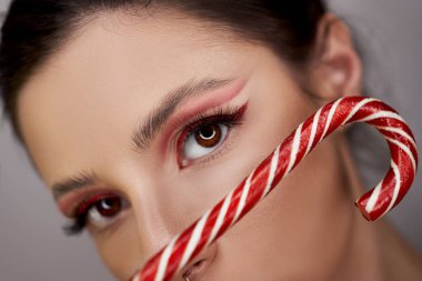 Parlak kırmızı göz makyajlı kadın ellerinde karamel, hatta güzel kaşları ve uzun kirpikleriyle.