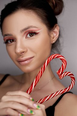 Parlak kırmızı göz makyajlı kadın ellerinde karamel, hatta güzel kaşları ve uzun kirpikleriyle.