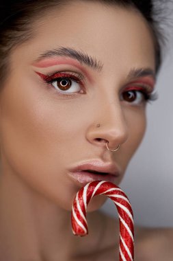 Parlak kırmızı göz makyajlı kadın ellerinde karamel, hatta güzel kaşları ve uzun kirpikleriyle.