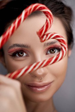 Parlak kırmızı göz makyajlı kadın ellerinde karamel, hatta güzel kaşları ve uzun kirpikleriyle.