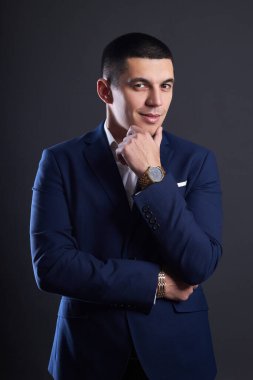 Stüdyoda koyu arka planda mavi ceketli bir iş adamının portresi. Kısa saçlı Mulatto adam. Genç kendine güvenen yönetici gülümsüyor