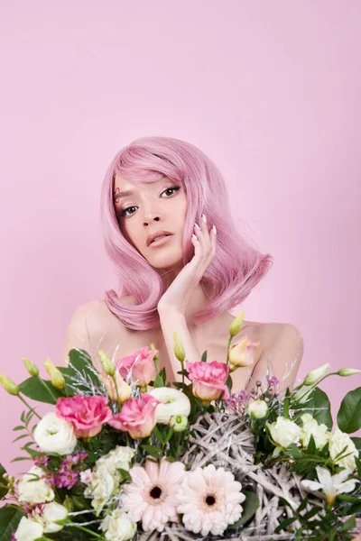 Portrait sexy young woman with pink hair, beautiful bouquet flowers in hand. Perfect hairstyle and hair coloring. Girl with beautiful eyes and long pink hair