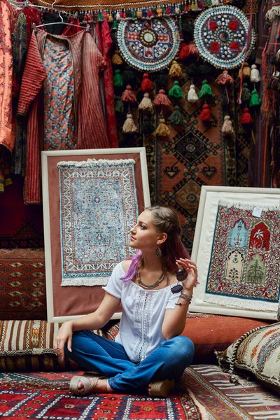 Woman chooses carpet at the market. Oriental bazaar of textiles. Factory for the production of carpets. Cheerful joyful emotions on the face woman