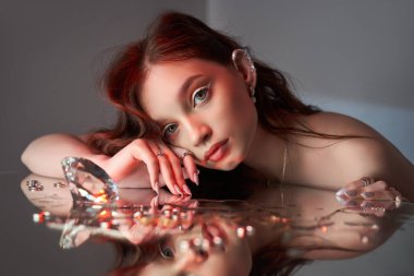 Yaratıcı makyajlı güzel bir kadın aynada yatıyor. Mücevherli romantik bir kadının güzel portresi.