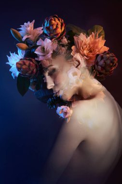 Çifte teşhirci bir kadının güzel çiçekli yüzü. Bir kızın portresi neon ışık ve renk, profesyonel makyaj, bir kadının çıplak arkası, kafasında çiçekler.