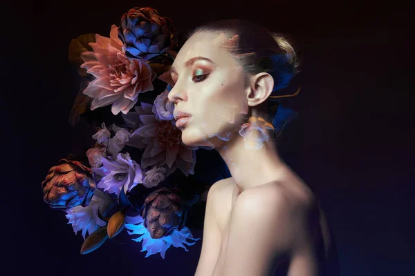 Beauty flowers face of a woman with double exposure. Portrait of a girl neon light and color, professional makeup, nude back of a woman, flowers in the head