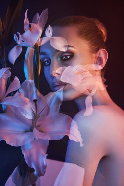 Çifte teşhirci bir kadının güzel çiçekli yüzü. Bir kızın portresi neon ışık ve renk, profesyonel makyaj, bir kadının çıplak arkası, kafasında çiçekler.