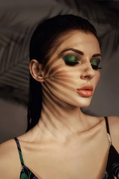 女孩脸上的棕榈叶阴影 漂亮的妆容热带肖像性感女子在叶子棕榈树 明亮的绿色化妆品 — 图库照片