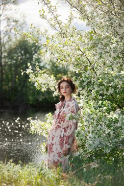 Güzel romantik kadın çiçek açan elma ağacının dallarında duruyor. Çiçeklerdeki bahar portresi kızı elma ağacı