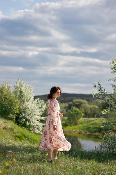 Uzun Elbiseli Genç Bir Kadın Göl Kenarındaki Bahar Bahçesinde Yürüyor — Stok fotoğraf