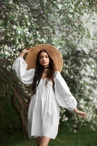 Kahverengi Saçlı Büyük Hasır Şapkalı Beyaz Elbiseli Bir Kadın Çiçek — Stok fotoğraf