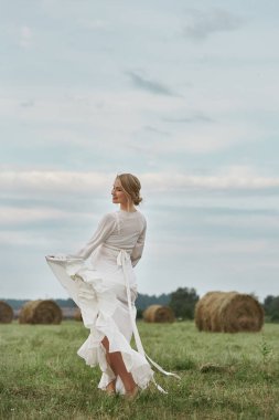 Hamile bir kadın, 9 aylık hamile. Yazın köyde, doğumdan birkaç gün önce, tarlada yürüyor.