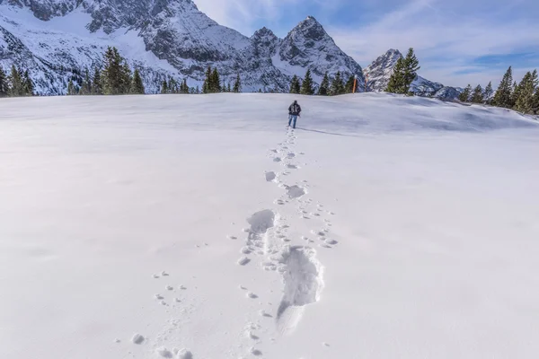 Homem caminhando através da neve em um pico de montanha — Fotografia de Stock