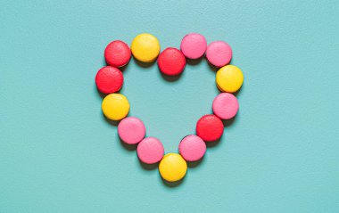 Yeşil arka planda kalp şeklinde dizilmiş çok renkli badem kurabiyeleriyle yatıyordu. Lezzetli ev yapımı kurabiyeler..