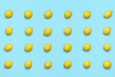 Above view with a pattern of lemons isolated on a blue-colored background. Lemons aligned symmetrically in rows on a blue table.
