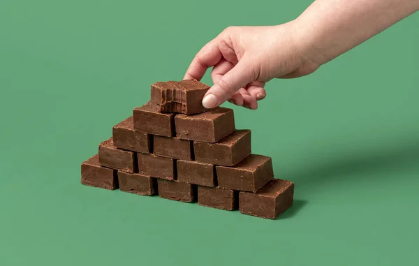 极简主义者用女人的手抓起巧克力软糖棒射击 一堆堆在绿色背景上的软糖条 — 图库照片
