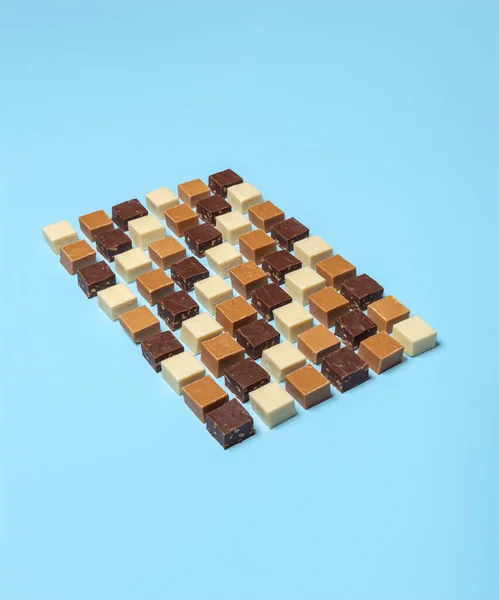 各种各样的自制软糖正方形对称地排列在蓝色的背景上 许多美味的软糖 厨房桌上的简约主义者 — 图库照片