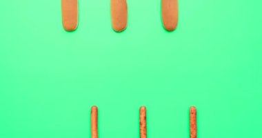 Yeşil arka planda üç sosisli minimalist ile hareket animasyonunu durdurun. Sosisli sandviç, çörek ve sosis yapmak yeşil arka planda ilerlemek. Fast food video animasyonu yemek..
