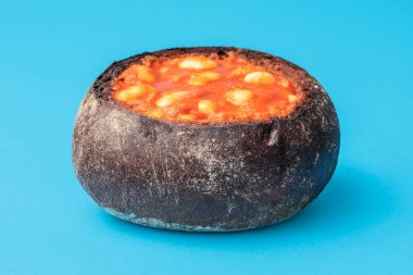 Ekmek kabuğunda fırında fasulye. Kahverengi ekmek hamuru, domates soslu beyaz fasulyeler için bir kâse gibi..