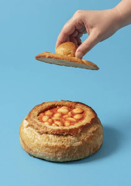 Baked beans in a bowl made from a loaf of bread. Traditional dish with boiled beans with tomato sauce in a bread crust.