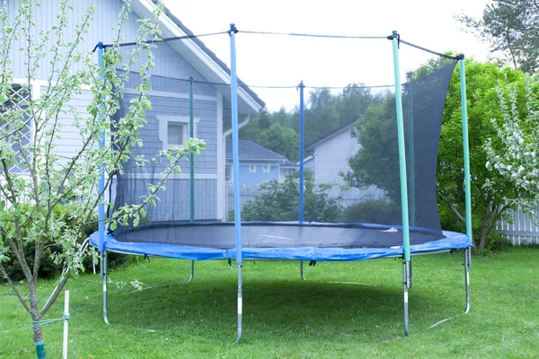 Blaues Trampolin auf dem Rasen im Garten — Stockfoto