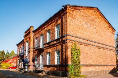 Partenosissus 'un kırmızı yapraklarıyla kaplı kırmızı tuğla binanın sonbahar manzarası.