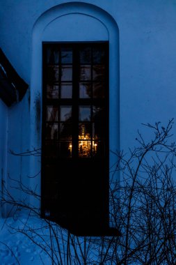 Kouvola, Finlandiya 'da Valkeala Kilisesi' nin penceresinden güzel bir avize ışığı süzülür.