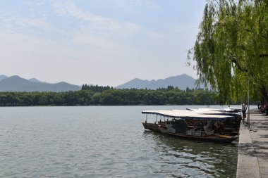 Batı Gölü 'ndeki tekne manzarası ve Hangzhou, Çin' deki Dağlar.