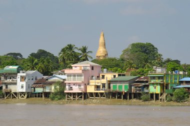 Yangon 'daki bir nehir kıyısındaki renkli evler ve altın pagoda.