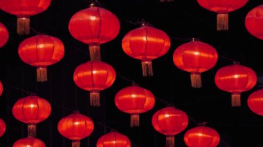 Karanlık bir arka planda asılı parlak kırmızı Çin fenerlerinin sergilenmesi bir kutlama ve kültürel şenlik hissi uyandırıyor..