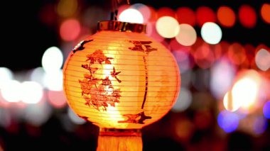 Çarpıcı bir Çin feneri, canlı bir bokeh arka planına sıcak bir ışık yayar. Kültürel kutlamalar ve neşeli toplantılar için mükemmel bir şenlik atmosferi yaratır..