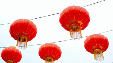 Parlak kırmızı Çin fenerleri elektrik kablolarından sarkıyor ve şehir ortamında şenlikli bir atmosfer yaratıyor..