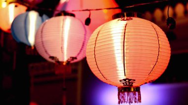 Canlı bir gece sahnesinde parlayan şenlikli kağıt fenerler, kültürel kutlamalar veya dekoratif ilham için mükemmel.