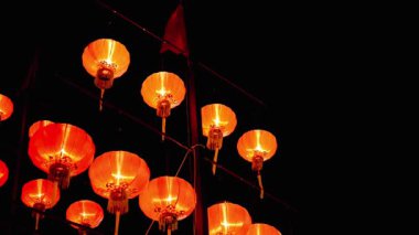 Karanlıkta asılı parlak kırmızı fenerler, gece şenlikli bir atmosfer yaratıyor.
