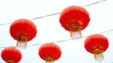 Açık bir günde elektrik kablolarından sarkan güzel kırmızı Çin fenerleri bir kutlama ve kültür geleneği hissi uyandırıyor.