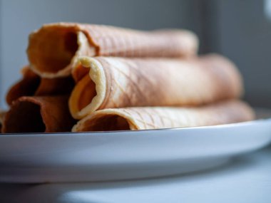 Yuvarlak gofret tüplerinin yan görüntüsü. Yumuşak sessiz arkaplan, editoryal ürün stili, parlak tabak sunumu,