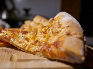 Erimiş peynirli pizza dilimi. Görünür bir çekiciliği ve sıcak iplikleri var. Kalın kabuğu, yumuşak kırıntıları var.