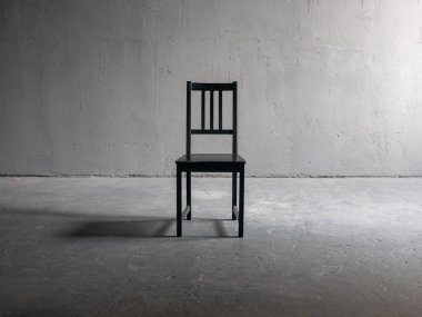 Yanlız ahşap sandalye, sert yan ışığı, derin gölgesi ve desenli alçı duvarlı, kumlu endüstriyel...