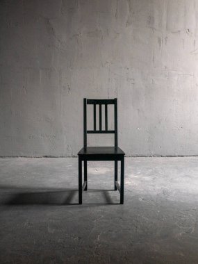 Yumuşak yönlü ışık ve yumuşak gölgesi olan tek bir ahşap sandalye. Tarafsız beton arka plan, minimalist.
