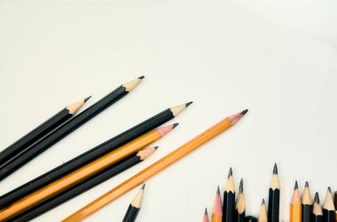 Bir tanesi yukarıyı gösteren bir sürü kalem. Resimde birçok kurşun kalem var. Bazıları siyah, bazıları turuncu.