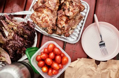 Canlı ve renkli piknik malzemeleri ızgara tavuk, taze organik domatesler ve çeşitli lezzetli salatalar.